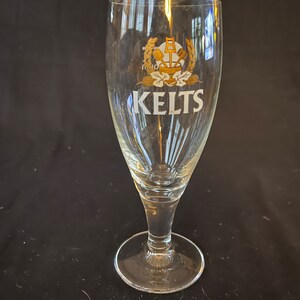 May include: A clear glass beer glass with a gold and white logo that says "Kelts".