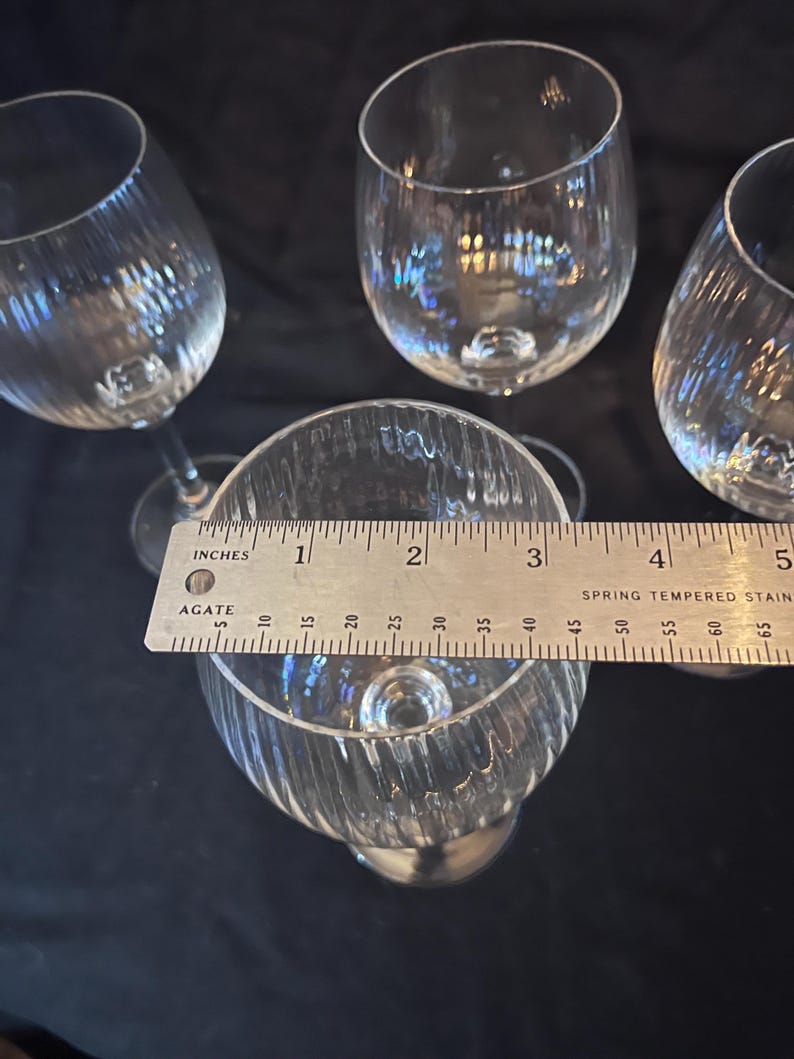 May include: Four clear wine glasses with a textured, ribbed design. The glasses are approximately 4 inches (10 cm) tall. The glasses are on a dark surface.