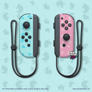 May include: Two Nintendo Switch Joy-Con controllers with custom skins. The left controller has a light blue skin with a pattern of white leaf shapes. The right controller has a pink skin with the same leaf pattern. Both controllers have black buttons and a black strap.