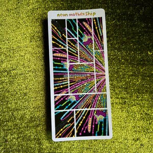 May include: A rectangular sticker with the text "neon mothership" at the top. The sticker features a colorful, geometric design with neon pink, yellow, blue, and green lines and shapes on a black background.