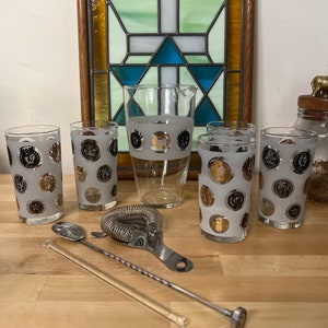 May include: A vintage cocktail set with a frosted glass pitcher and six frosted glasses with a gold and black polka dot pattern. The set includes a bar spoon, a cocktail shaker, and a strainer.