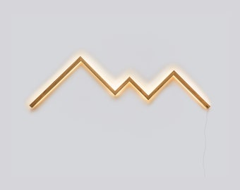 May include: A wooden wall light in the shape of a mountain range with a warm white glow. The light is made of thin strips of wood and has a simple, modern design.