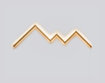 May include: A wooden wall light fixture shaped like a mountain range with a warm white glow.