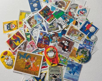 Puede incluir: Una colección de coloridos sellos postales con diversos diseños. Los sellos representan personajes de dibujos animados, animales e ilustraciones, incluyendo Superman, Doraemon y un zorro. Algunos sellos tienen texto como "Nippon" y "Magyar Posta".