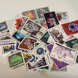 Peut inclure: Une collection de timbres colorés représentant divers minéraux et pierres précieuses. Les timbres proviennent de différents pays, notamment la Bulgarie, le Kenya, la Nouvelle-Zélande, le Zimbabwe et la Roumanie. Les timbres sont de tailles et de formes variées, et certains comportent du texte dans différentes langues.