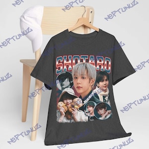 Puede incluir: Camiseta gris oscuro con el nombre "SHOTARO" en una fuente retro. La camiseta muestra m&uacute;ltiples im&aacute;genes de una persona, con una est&eacute;tica vintage. Una gorra de b&eacute;isbol blanca es visible en el fondo.