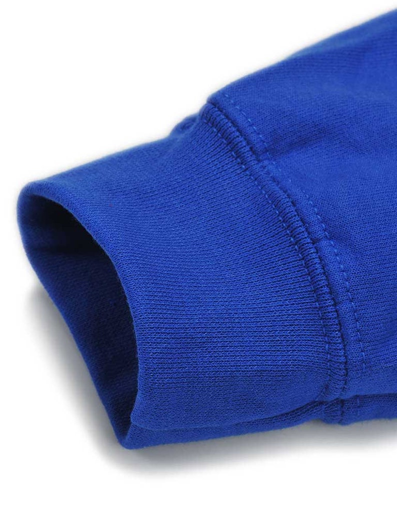 K&ouml;nnte beinhalten: Nahaufnahme eines k&ouml;nigsblauen Sweatshirt-&Auml;rmelb&uuml;ndchens. Das B&uuml;ndchen ist gerippt und hat eine doppelt gen&auml;hte Naht. Der Stoff scheint ein weiches Strickmaterial zu sein. Der &Auml;rmel ist leicht angewinkelt.