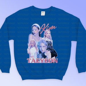 K&ouml;nnte beinhalten: K&ouml;nigsblaues Sweatshirt mit einer Grafik von vier Frauen, dem Namen "Kim" in rosa Schrift und "TAEYEON" in rosa Blockbuchstaben. Das Sweatshirt hat einen Rundhalsausschnitt.