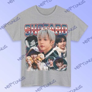 Puede incluir: Camiseta gris con un dise&ntilde;o gr&aacute;fico retro. El dise&ntilde;o presenta el nombre "SHOTARO" en letras rojas, blancas y azules, junto con varias im&aacute;genes de una persona, creando una est&eacute;tica vintage.