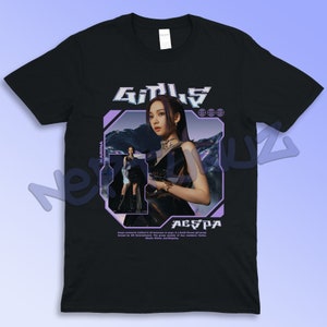 Puede incluir: Camiseta negra con un gr&aacute;fico de una mujer y la palabra "GIRLS" en una fuente futurista. La camiseta tambi&eacute;n incluye el nombre "KARINA" y el nombre del grupo "AESPA". El dise&ntilde;o utiliza colores morados y blancos.