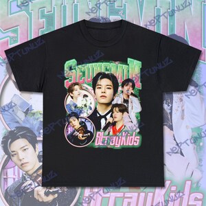Puede incluir: Camiseta negra con un collage de im&aacute;genes de un miembro de un grupo musical, con el nombre "Seungmin" en letras verdes y rosas. Las palabras "Stray Kids" est&aacute;n en rosa debajo de las im&aacute;genes.