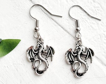 May include: A pair of silver dragon earrings with a detailed design. The earrings are on a white background.