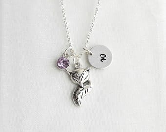 May include: A silver-toned necklace featuring a fox-shaped pendant, a small round charm stamped with the letter W, and a circular light purple crystal charm. The delicate chain connects to these three distinct charms hanging together.