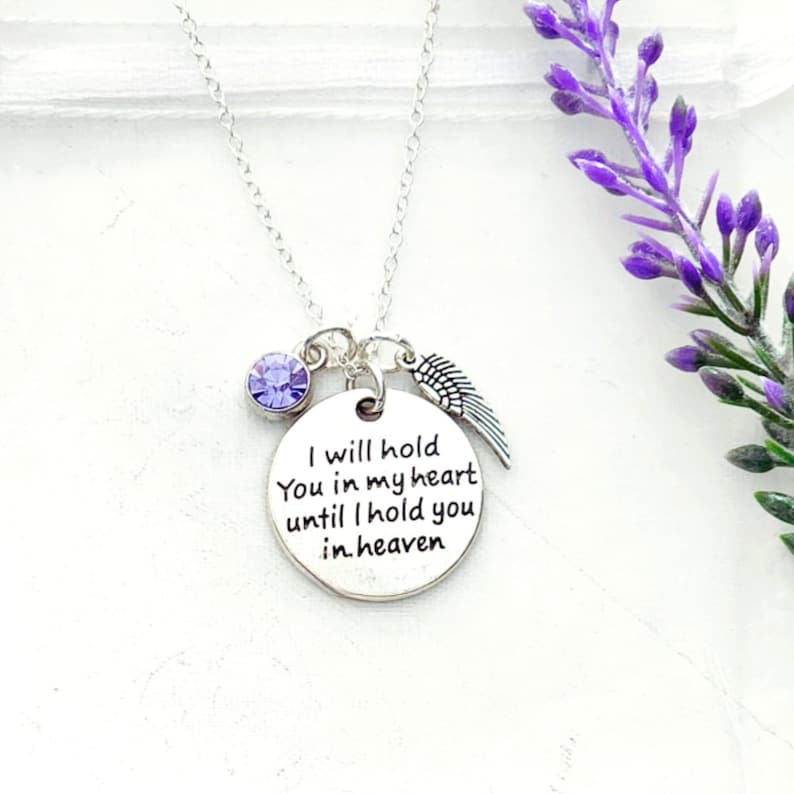 Pu&ograve; includere: Collana d'argento con un ciondolo rotondo che recita "Ti terr&ograve; nel mio cuore finch&eacute; non ti terr&ograve; in paradiso". Il ciondolo &egrave; attaccato a una catena d'argento con un piccolo cristallo viola e un ciondolo a forma di ala d'angelo d'argento.