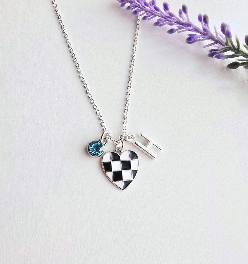 May include: A silver necklace with a checkered heart charm, a blue crystal charm, and a silver letter 'H' charm.
