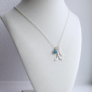 Puede incluir: Un collar de plata con un dije de cristal azul, un dije de palo de hockey y un dije con la letra "C".