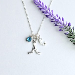 Puede incluir: Collar de plata con un cristal azul, un dije de palo de hockey y un dije de la letra C.