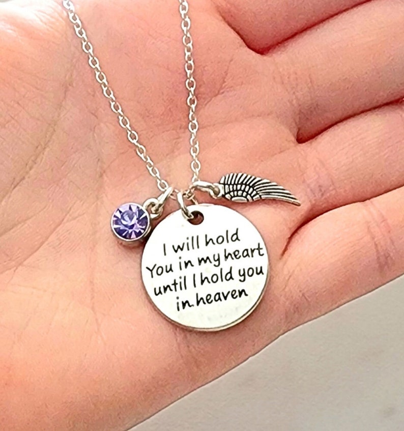 Pu&ograve; includere: Collana d'argento con un ciondolo rotondo che recita "Ti terr&ograve; nel mio cuore finch&eacute; non ti terr&ograve; in cielo". Il ciondolo &egrave; attaccato a una catena d'argento con un piccolo cristallo viola e un ciondolo ad ala d'angelo d'argento.
