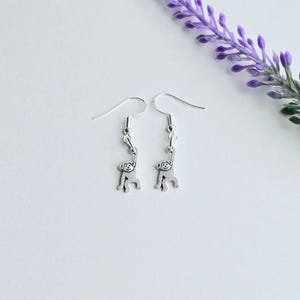 May include: A pair of silver dangle earrings featuring a small monkey charm hanging from each earring.