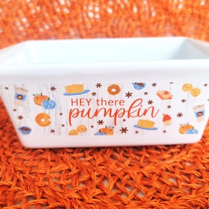 May include: White rectangular ceramic baking dish with the text "Hey there pumpkin" in orange script. The dish is decorated with fall-themed illustrations of pumpkins, donuts, and coffee cups.
