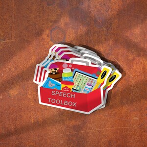 A pile of sticker that says speech toolbox is on a desk.  The image includes a red toolbox with various speech therapy toys and tools.
