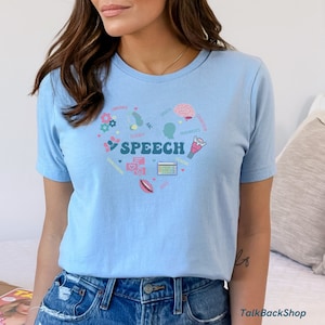 May include: Light blue t-shirt with a graphic design of a heart with the word "SPEECH" in the center. The heart is surrounded by icons representing different aspects of speech, such as language, fluency, articulation, and pragmatics.