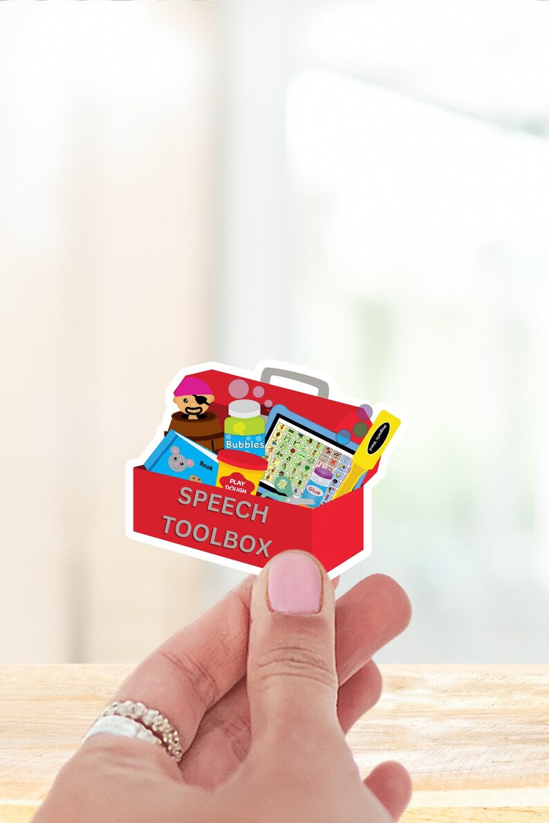May include: A red toolbox with a white outline and the words "Speech Toolbox" on the front. The toolbox is open and filled with various items, including a book, play dough, bubbles, a toy pirate, and a yellow ruler.