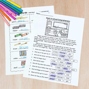 May include: Two worksheets with school-themed exercises are on a light wood surface. One worksheet focuses on plurals, the other is a reading comprehension activity. Colored pencils are in the upper left corner. The text includes "Back to School Comprehension".