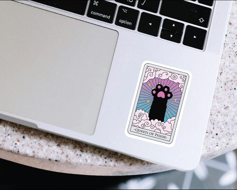 K&ouml;nnte beinhalten: Eine Tarotkarte mit einem rosa, blauen und violetten Hintergrund. Die Karte zeigt einen schwarzen Pfotenabdruck mit rosa Pfotenballen. Der Text auf der Karte lautet "Queen of Paws".