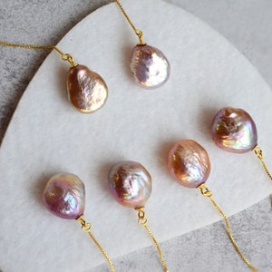 May include: Five iridescent pink and gold pearl pendants on delicate gold chains. The pearls are various shapes and sizes.