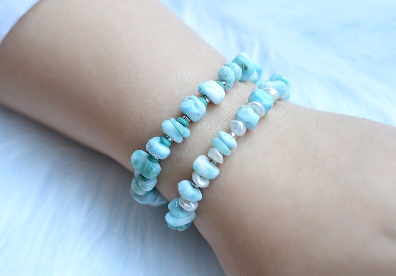 Puede incluir: Dos pulseras el&aacute;sticas con piedras Larimar azul claro pulidas e irregulares. Una pulsera est&aacute; acentuada con peque&ntilde;as cuentas turquesas, mientras que la otra se alterna con peque&ntilde;as perlas de agua dulce blancas y separadores plateados.