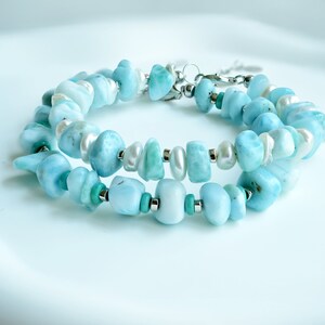 Puede incluir: Una pulsera de varias hebras con piedras preciosas pulidas de color azul claro, perlas de agua dulce blancas y peque&ntilde;as cuentas de turquesa intercaladas con espaciadores de metal plateado. Incluye un cierre de mosquet&oacute;n plateado.