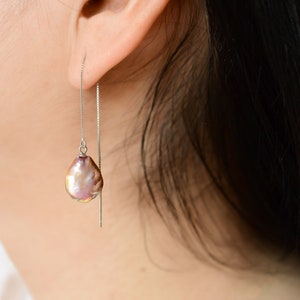 May include: A pair of silver dangle earrings with a single iridescent purple pearl drop on each earring.