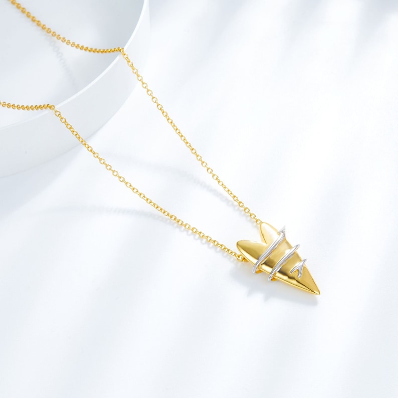May include: A gold necklace with a heart-shaped pendant. The pendant is made of two metals, gold and silver, and has a unique design.