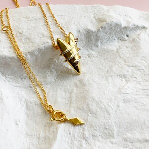 May include: A gold necklace with a heart-shaped pendant. The pendant is made of two different metals, one gold and one silver, and is twisted together to create a unique design.