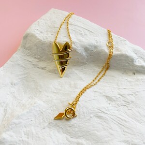 May include: A gold necklace with a heart pendant. The heart is made of twisted wire and has a delicate, intricate design.