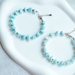 Puede incluir: Dos pulseras con cuentas de piedra azul claro, irregulares y pulidas. Una pulsera incluye peque&ntilde;as cuentas espaciadoras de color turquesa, mientras que la otra presenta perlas blancas de forma ovalada. Ambas tienen cierres y cadenas de metal plateado.