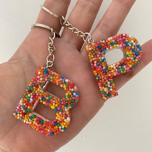 May include: A keychain with two letter charms, "B" and "P", made of clear resin filled with colourful sprinkles.