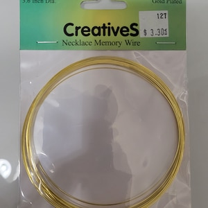 Peut inclure: Un paquet de 12 boucles de fil mémoire en acier inoxydable plaqué or, chacune mesurant 9,1 cm de diamètre. L'emballage est étiqueté "Creatives Necklace Memory Wire" et porte une étiquette de prix de 3,30 $.