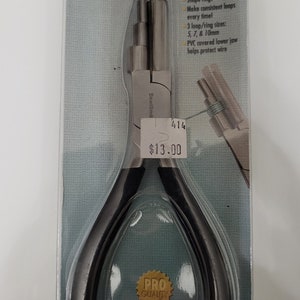 Puede incluir: Una herramienta de bucle de alambre negra y plateada con un mango negro y una mandíbula plateada. La herramienta está empaquetada en una bolsa de plástico transparente con una etiqueta blanca y azul que dice "Wire Looper" y "PRO QUALITY". La etiqueta también enumera las características de la herramienta, incluida la capacidad de dar forma a los anillos, hacer bucles consistentes y los diferentes tamaños de bucles disponibles. El precio de la herramienta se indica en 13,00 €.