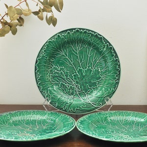 Puede incluir: Tres platos de cerámica verde con un diseño de hojas. Los platos son de diferentes tamaños y están dispuestos en una fila sobre una mesa de madera.