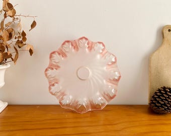 Könnte beinhalten: Eine Vintage-Deckenleuchte aus mattiertem Glas mit gerüschtem Rand. Die Leuchte hat eine zarte rosa Farbe mit dunklerem rosa Besatz. Die Leuchte hat eine kreisförmige Mitte und ein Wirbeldesign.