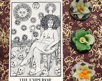 Könnte beinhalten: Die Tarotkarte Der Kaiser zeigt eine Schwarzweißillustration einer nackten Figur, die auf einem Thron sitzt, umgeben von Schädeln. Die Figur hat lockiges Haar und hält eine Kugel auf ihrem Schoß. Die Karte ist mit "Der Kaiser" betitelt und trägt die römische Ziffer IV in der oberen rechten Ecke.
