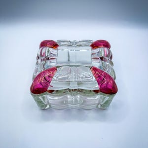 Caja de baratijas de cristal color arándano antiguo con esquinas de rubí rojo.