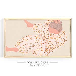 May include: A rectangular gold-framed digital artwork titled WISHFUL GAZE Frame TV Art. The image depicts a figure in light pink pajamas with an orange cross-stitch pattern, curled in a reclining position against a solid light beige background.