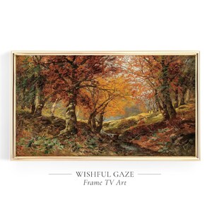 May include: A rectangular landscape painting in a thin gold frame depicting an autumn forest scene with orange, red, and brown foliage, thick tree trunks, and a small stream flowing through the center. The text WISHFUL GAZE Frame TV Art is below.