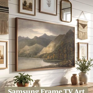 May include: A display of framed art and decorative items on a white wall, including a large landscape painting and smaller framed pictures. A wooden cabinet below holds plants and vases. The text "Samsung Frame TV Art" is visible.
