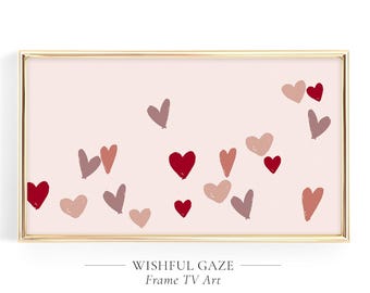 May include: A rectangular digital art display framed in thin gold metal, featuring a light pink background scattered with various hand-drawn heart shapes in shades of deep red, muted rose, and soft mauve, with the text WISHFUL GAZE Frame TV Art.