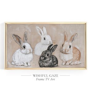 May include: A framed artwork featuring five rabbits in various colors: white, black, and tan. The rabbits are depicted on a neutral background. The artwork is framed in a gold-colored frame. Text at the bottom reads "WISHFUL GAZE Frame TV Art."