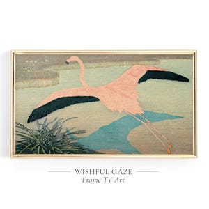 May include: A rectangular framed wall art piece featuring a stylized illustration of a pink flamingo in flight over a muted green and brown landscape with a patch of dark green grass in the lower left corner and black wing tips on the bird.